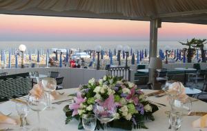 a table with a centerpiece of flowers and wine glasses at Hotel Montecarlo in Lido di Jesolo