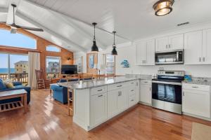 a kitchen with white cabinets and a living room at In Due Tide in Rodanthe