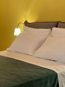 Una cama con almohadas blancas y una lámpara. en Magnificat, en Palermo