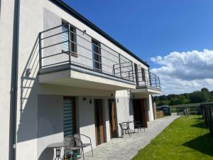 a building with a balcony with chairs and tables at Apartamenty Paradise in Tupadła