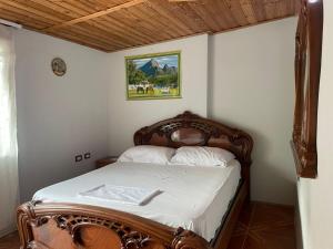 a bedroom with a wooden bed with white sheets at Berat Guesthouse Katerina in Berat