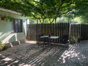 eine Terrasse mit einem Tisch und Stühlen vor einem Zaun in der Unterkunft Căsuța Verde in 2 Mai + 8 Fotos