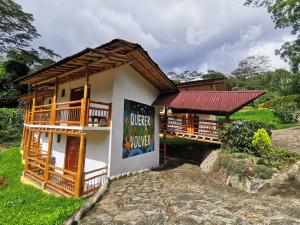 a house with a balcony and a sign on it at Hotel y termales Las Heliconias in Zetaquira