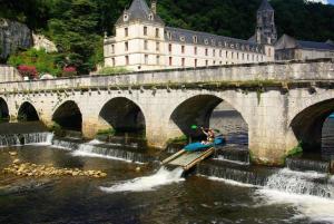 a person on a raft in the water under a bridge at Duplex 4 personnes avec jardin in Brantôme