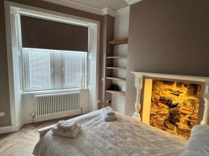 Un dormitorio con chimenea con toallas en una cama. en Largs Sandringham Apartment, en Largs