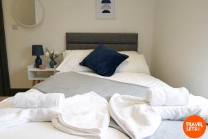 a bed with white towels on it with a blue pillow at Private Double Rooms By Travel Lets Short Term Rental Agency Derry in Derry Londonderry