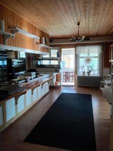 une grande cuisine avec des plafonds en bois et un grand îlot dans l'établissement Gula Villan Värdshus, à Glommersträsk