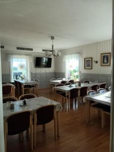 un restaurant avec des tables et des chaises et une télévision à écran plat dans l'établissement Gula Villan Värdshus, à Glommersträsk