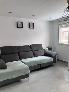 a living room with a black couch and a window at Alojamientos centro in Yecla