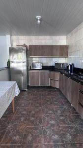 eine Küche mit einem Kühlschrank aus Edelstahl und einem Tisch in der Unterkunft Casa das Palmeiras - 80 metros do mar in Navegantes