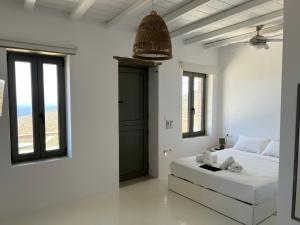 a white bedroom with a white bed and windows at La Priva Calma in Agios Ioannis