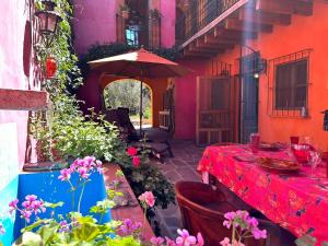 a patio with a table with an umbrella and flowers at Posada de la cruz #4 in Querétaro