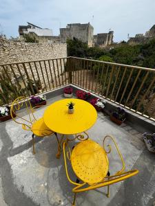 a yellow table and two chairs on a balcony at Nina in Siġġiewi