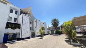 a row of white buildings with palm trees on a street at Hotel Leblanc Suites in Puerto La Cruz