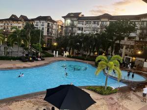 a large swimming pool with people in a resort at 1 Bedroom unit with balcony and facing amenities and just beside SM Ecoland in Davao City