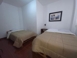 Dos camas en una habitación con paredes blancas. en Hospedaje Grau, en Puerto Chicama