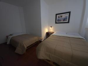 Un dormitorio con dos camas y un cuadro en la pared. en Hospedaje Grau, en Puerto Chicama