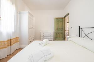 a white bedroom with a large white bed and a window at AffittaSardegna - Trilo Euforbia in Santa Lucia