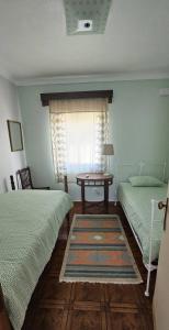 ein Schlafzimmer mit zwei Betten und einem Tisch und einem Fenster in der Unterkunft Casa da Praia - Group Accommodation in Praia da Vitória