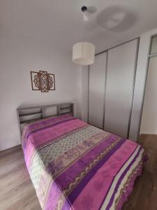 a bedroom with a bed with a purple comforter at Temporariorosario10 in Rosario