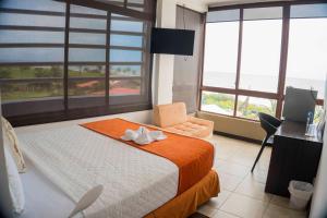 a bedroom with a bed with a chair and windows at Hotel Punta Azul in Pedernales
