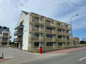 an apartment building with a red fire hydrant in front of it at Dune & Sea in Ustronie Morskie