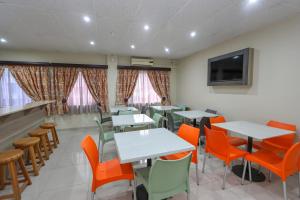 a dining room with tables and chairs and a tv at PLM Palace Lodge in Durban