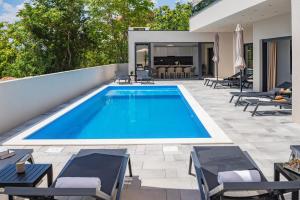 einen Pool auf einer Terrasse mit Stühlen und einem Haus in der Unterkunft Villa Bellezza A Luxurious Retreat in Imotski in Imotski
