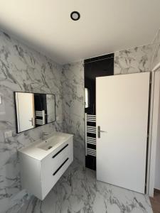 ein Badezimmer mit einem weißen Waschbecken und einem Spiegel in der Unterkunft Maison La Pornicaise 11 in Saint-Jean-de-Monts + 2 Fotos