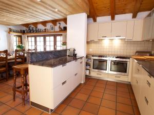 a large kitchen with white cabinets and a table at Chalet Huwi Zermatt in Zermatt