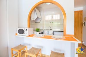 a kitchen with a counter with a microwave and chairs at Cordoba IBERPLAYA in Salou
