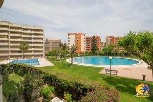 a swimming pool in a park with buildings in the background at Cordoba IBERPLAYA in Salou