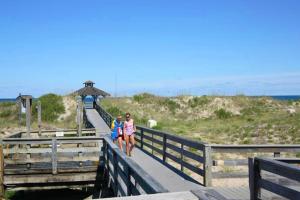 two people walking on a boardwalk at the beach at Let Me Count The Waves in Corolla