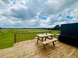a wooden deck with a picnic table and a couch at Unique Suffolk Cabin with Countryside Views in Burgh