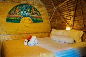 a bedroom with a bed with a painting on the wall at Samui Circus Studio & Ville - Dome Bungalow 5 in Amphoe Koh Samui