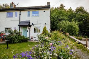 a white house with flowers in the yard at Wells Cottage in Holmfirth