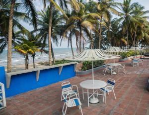 a patio with tables and chairs and the beach at Vista al Mar Residencias Laguna Blanca in Tucacas