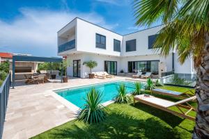 a villa with a swimming pool and a backyard at Luxury Villa Olivetum with Heated Pool, Sea View & Sauna - Okrug Gornji in Trogir