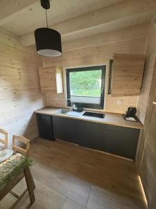 eine Küche in einer Holzhütte mit einem Waschbecken und einem Fenster in der Unterkunft Szare Domki in Mrzeżyno + 62 Fotos