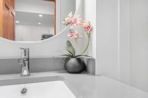 a bathroom sink with a vase with flowers in it at Amazing Village Location with PRIVATE Hot Tub in Whistler +27 photos