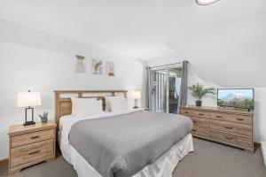 a white bedroom with a large bed and a window at Amazing Village Location with PRIVATE Hot Tub in Whistler