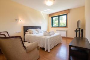 ein Schlafzimmer mit einem Bett und einem Stuhl und einem Fernseher in der Unterkunft Gavian House in A Coruña