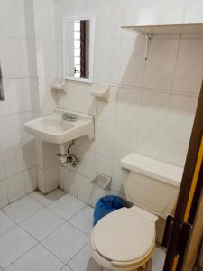 a white bathroom with a toilet and a sink at Depa 02 Con Cochera Acceso Directo Torre Belen in Mazatlán