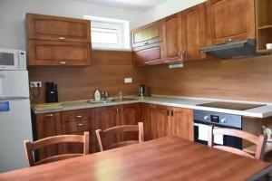 a kitchen with wooden cabinets and a wooden table with chairs at Chata LANOVKA - Vojtechova samota in Spišská Nová Ves