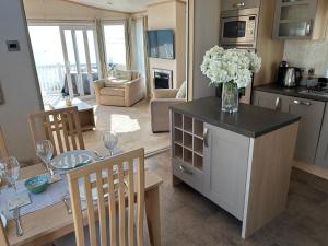a kitchen and living room with a table with a vase of flowers at Knightsbridge 2 Bedroom Lodge in Lytchett Minster
