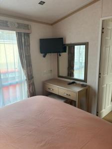 a bedroom with a bed and a mirror and a television at Knightsbridge 2 Bedroom Lodge in Lytchett Minster