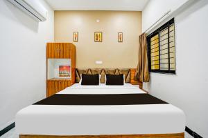 a bedroom with a large white bed and a window at Hotel O katyayani in Indore