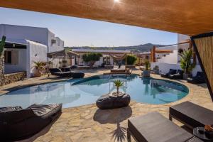 a large swimming pool in a yard with chairs at Olive Mykonos Villas in Ano Mera