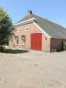 a red brick building with a red garage at B&B Bij Greet in Sellingen