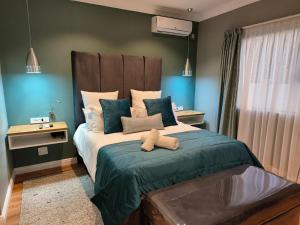 a bedroom with a large bed with blue walls at Bel-Air Guesthouse in Klerksdorp